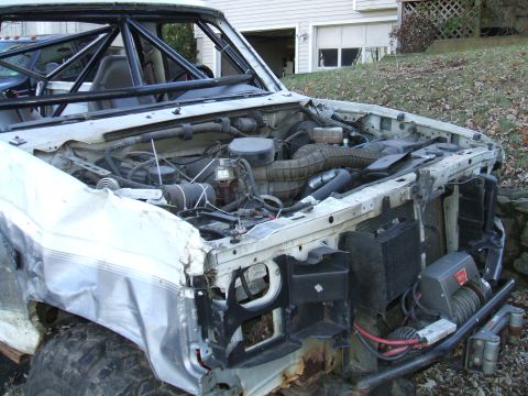 1995 Ford Bronco - Modified 1995 Ford Bronco engine bay shows roll cage and winch, ready for off-road use.