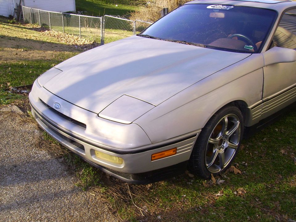 Silver coupe with pop-up headlights parked on grass
