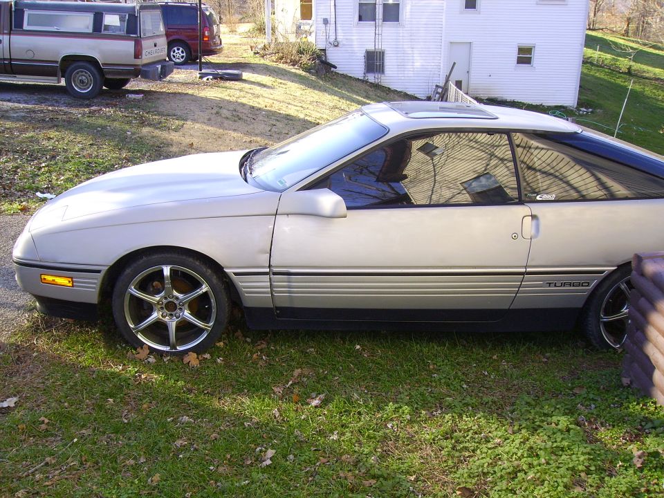 Silver 1989 Ford Probe coupe with aftermarket wheels and a sunroof, parked on grass