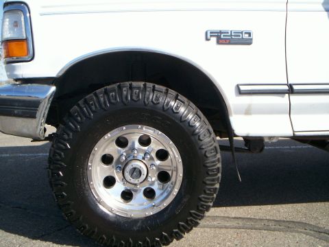 1992 Ford F-250 - Close-up of the front fender and wheel of a white 1992 Ford F-250 XLT pickup truck.