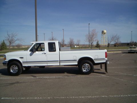 1992 Ford F-250 - A white 1992 Ford F-250 crew cab pickup truck is parked in a lot under a clear blue sky.