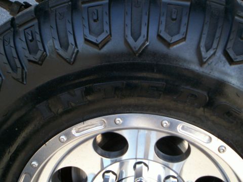 1992 Ford F-250 - Detail of a tire and chrome wheel, with partial text visible on the tire's sidewall.