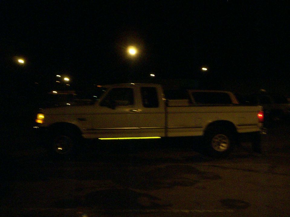 Side view of a white 1992 Ford F-250 pickup truck at night