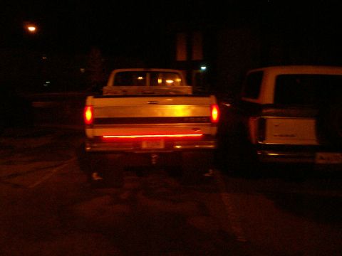 1992 Ford F-250 - A white Ford pickup truck is seen from the rear at night, with another vehicle parked to its right.
