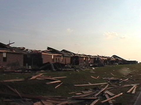 1979 Ford Bronco - The aftermath of a tornado shows extensive damage to a row of buildings and debris strewn across the landscape.