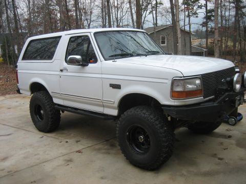 1996 Ford Bronco - Clean white full-size Ford Bronco with the hardtop on, parked on a concrete driveway and shot from the passenger-side 3/4 front in a bare w…