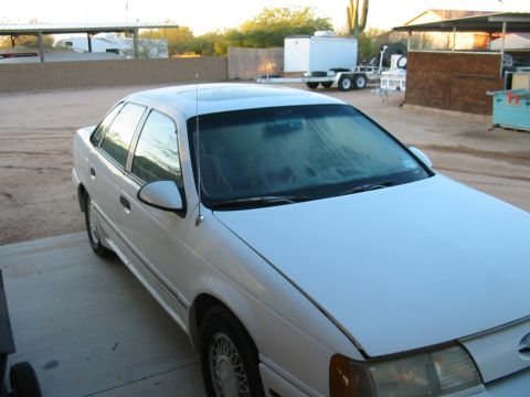 1993 Ford Taurus - White 1993 Ford Taurus sedan parked in an outdoor lot with a trailer visible behind it.