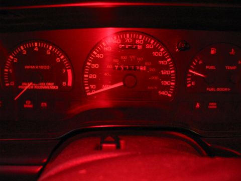 1993 Ford Taurus - Interior view of a 1993 Ford Taurus dashboard, illuminated in red, displaying all gauges.