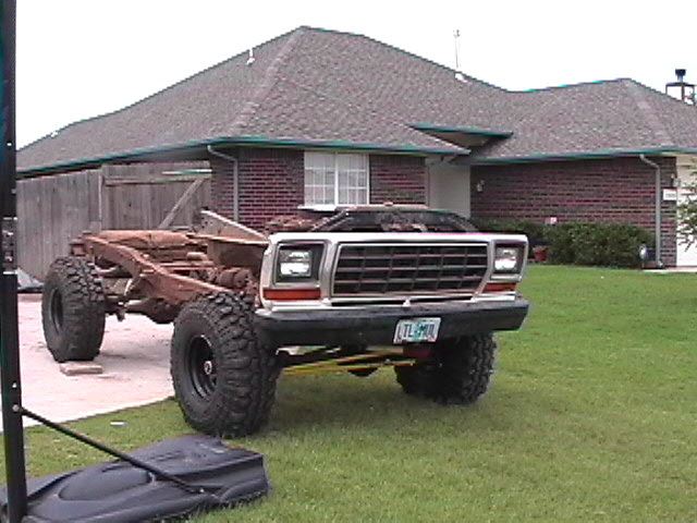 Late-1970s Ford pickup front clip beside a bare frame on a residential lawn