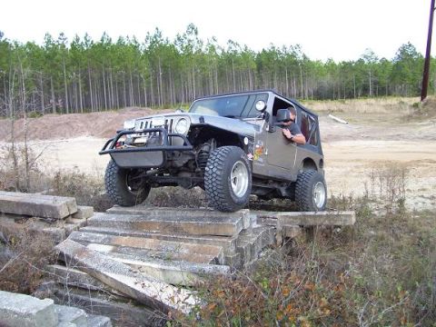 2004 Jeep TJ - A gray Jeep Wrangler TJ navigates a challenging off-road course over concrete barriers.