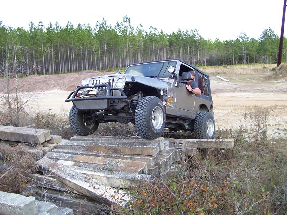 Gray Jeep Wrangler TJ driving over concrete obstacles