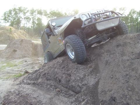 2004 Jeep TJ - Jeep TJ navigates an off-road obstacle, showing its suspension and tires.
