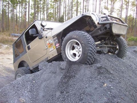 2004 Jeep TJ - A tan Jeep Wrangler navigates a steep incline of gravel, its off-road capabilities.