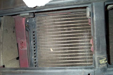 1996 Ford Bronco - Close-up view of a vehicle's radiator grille, showing the metal fins and surrounding red and black framing.