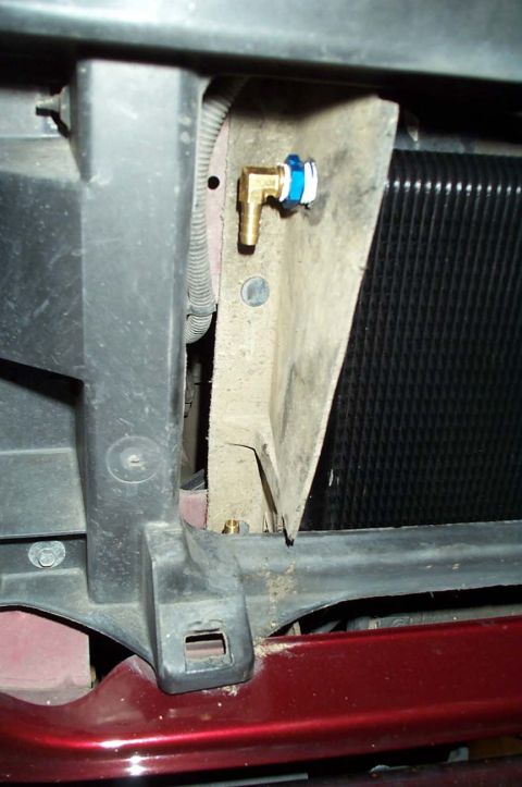1996 Ford Bronco - A brass fitting with blue and white tape is attached to the radiator support structure.