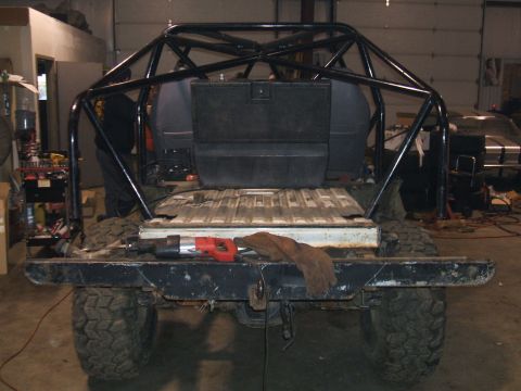 1995 Ford Bronco - This heavily modified vehicle, possibly an SUV, is undergoing work in a garage, a prominent roll cage.
