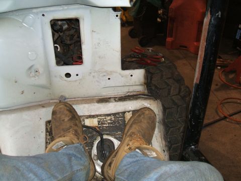 1995 Ford Bronco - The interior of a vehicle shows exposed metal and a spare tire, suggesting it is undergoing repairs.