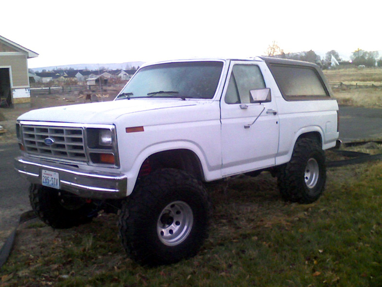 White 1980 Ford Bronco with lifted suspension and large tires, front 3/4 view