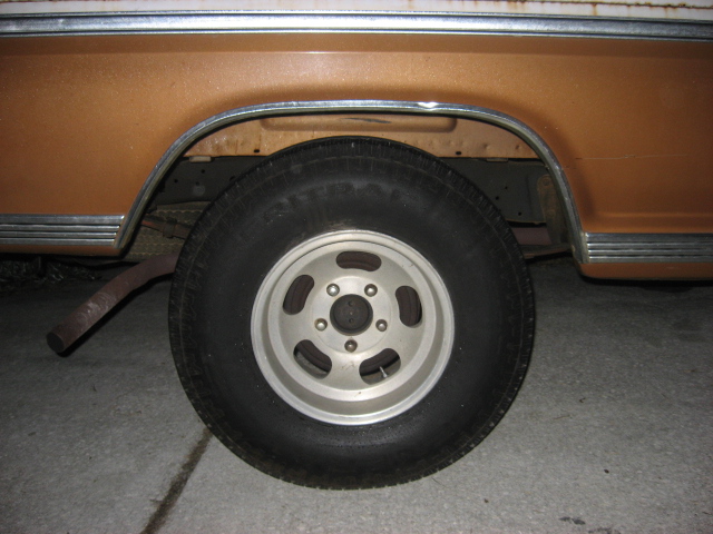 Brown truck rear wheel with chrome trim and exhaust pipe