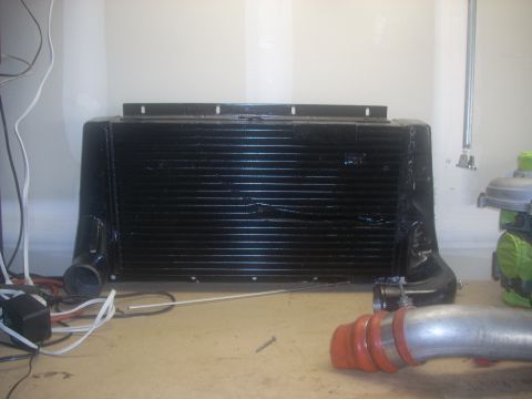 1991 Ford Mustang - A black intercooler unit is shown with associated silver piping and red couplers, likely for an automotive application.