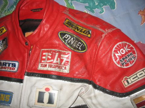 2005 Yamaha R1 - This close-up shows a red and white leather motorcycle jacket adorned with various racing sponsor patches.