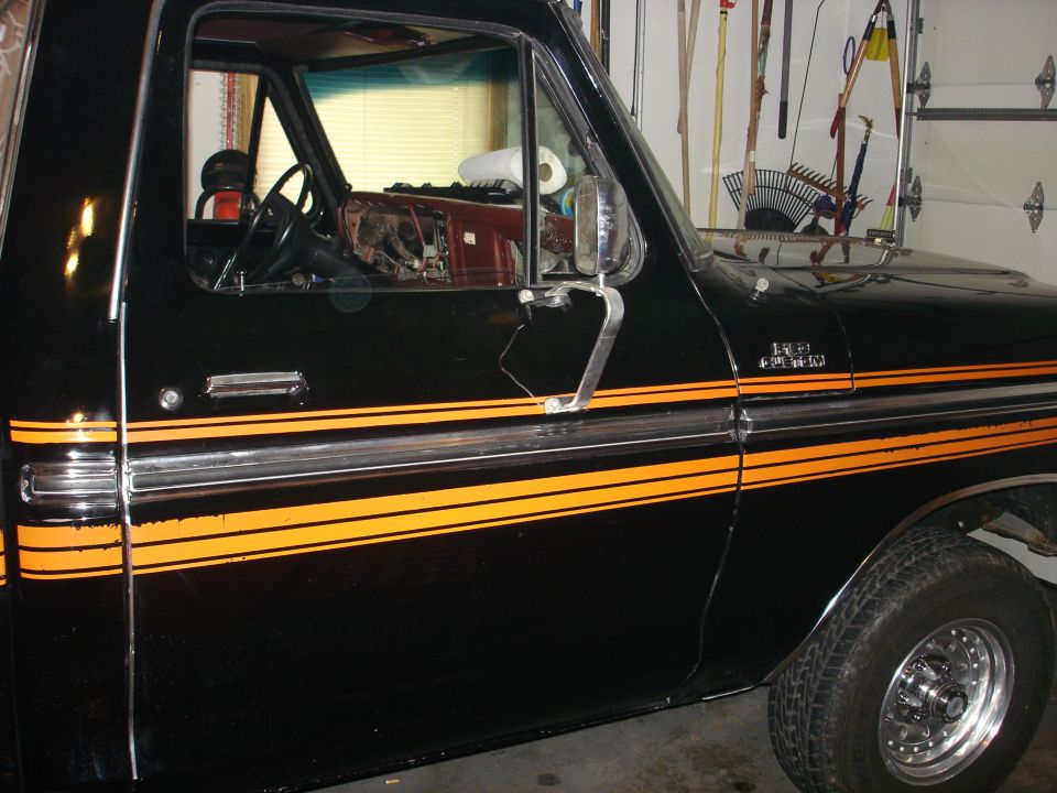 Side view of a black 1979 Ford F-150 with orange stripe decals on the door and fender