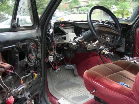 1985 Ford Bronco - The interior of a vehicle is shown with the dashboard disassembled and wiring exposed.