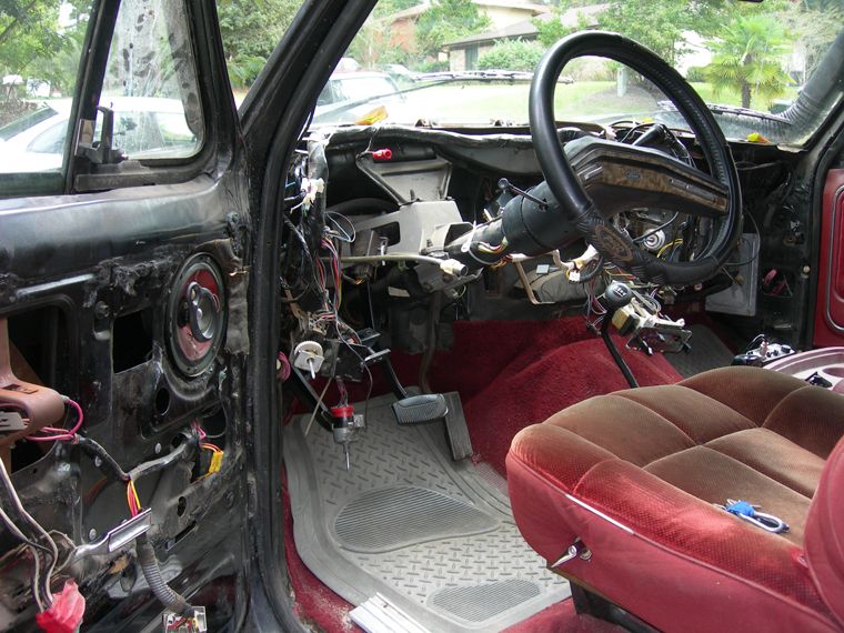 Vehicle interior with dashboard removed, wires exposed, and seats visible