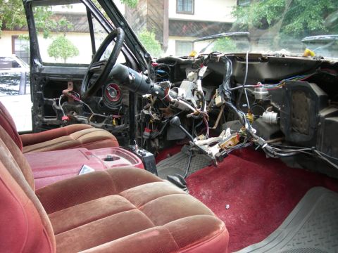1985 Ford Bronco - The interior of a vehicle shows significant disassembly, with exposed wiring and components visible around the dashboard.