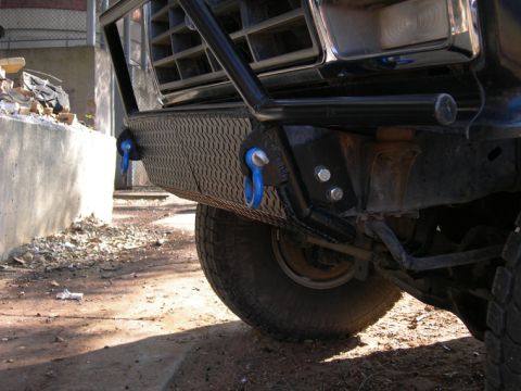 1985 Ford Bronco - Custom front bumper with integrated tow hooks on a truck, showing the grille and suspension components.