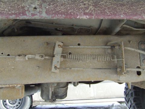 1990 Ford Bronco - Close-up view of the brake cable assembly and frame components on a vehicle's undercarriage.