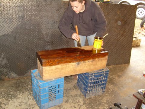 1974 Ford Bronco - Woman stains a wooden box on milk crates, with a trailer visible in the background.