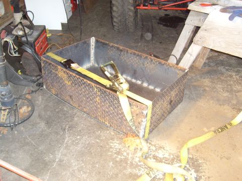 1974 Ford Bronco - A diamond plate metal box secured with yellow ratchet straps sits on a concrete floor.