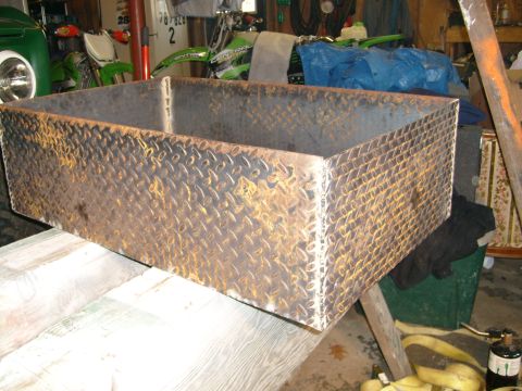 1974 Ford Bronco - Metal box with diamond plate texture sits on a wooden surface in a garage setting.