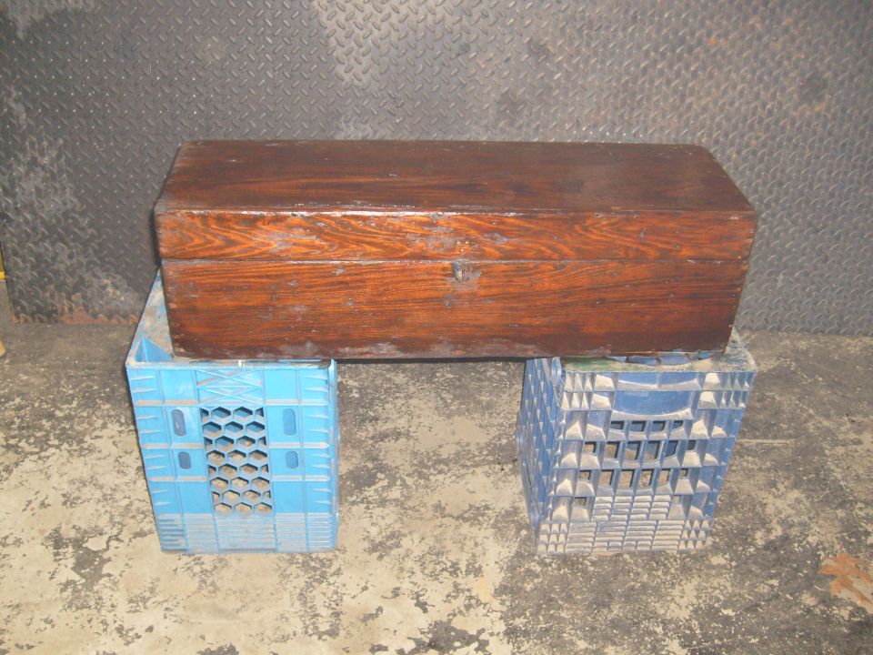 Wooden chest on blue and white milk crates against a diamond plate wall