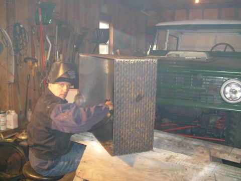 1974 Ford Bronco - Man welding in a garage, with a 1974 Ford Bronco visible behind him.