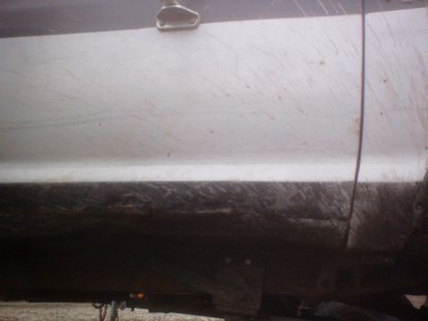 1990 Ford Ranger - A close-up view of a mud-splattered white truck door and its dark lower body panel.