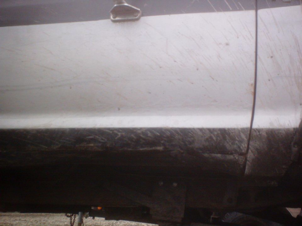 White truck door covered in mud streaks, with a dark lower body panel