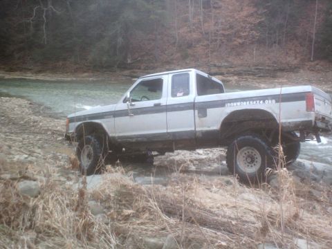 1990 Ford Ranger - A white 1990 Ford Ranger navigates a rocky stream bed, demonstrating its off-road capabilities.