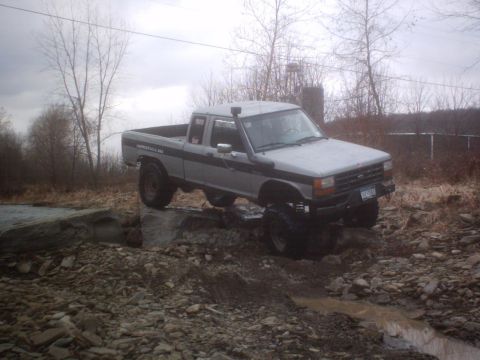 1990 Ford Ranger - A modified pickup truck is shown traversing a challenging rocky path.