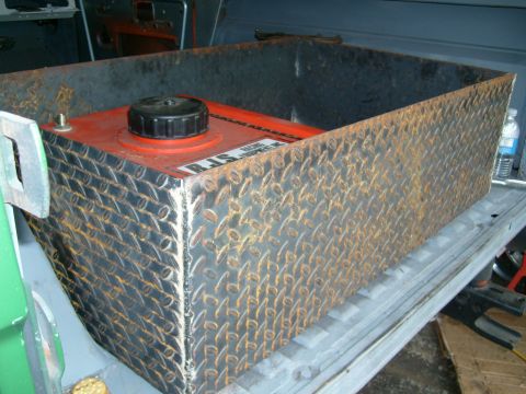 1974 Ford Bronco - Auxiliary fuel tank with visible text 'RJS' on its side, placed inside a vehicle's cargo area.