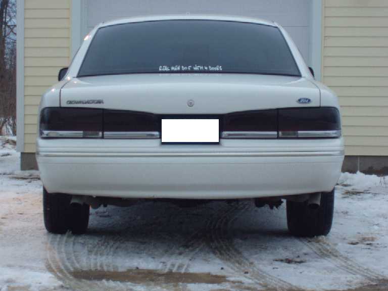 Rear of white Ford sedan with tinted taillights on snowy driveway