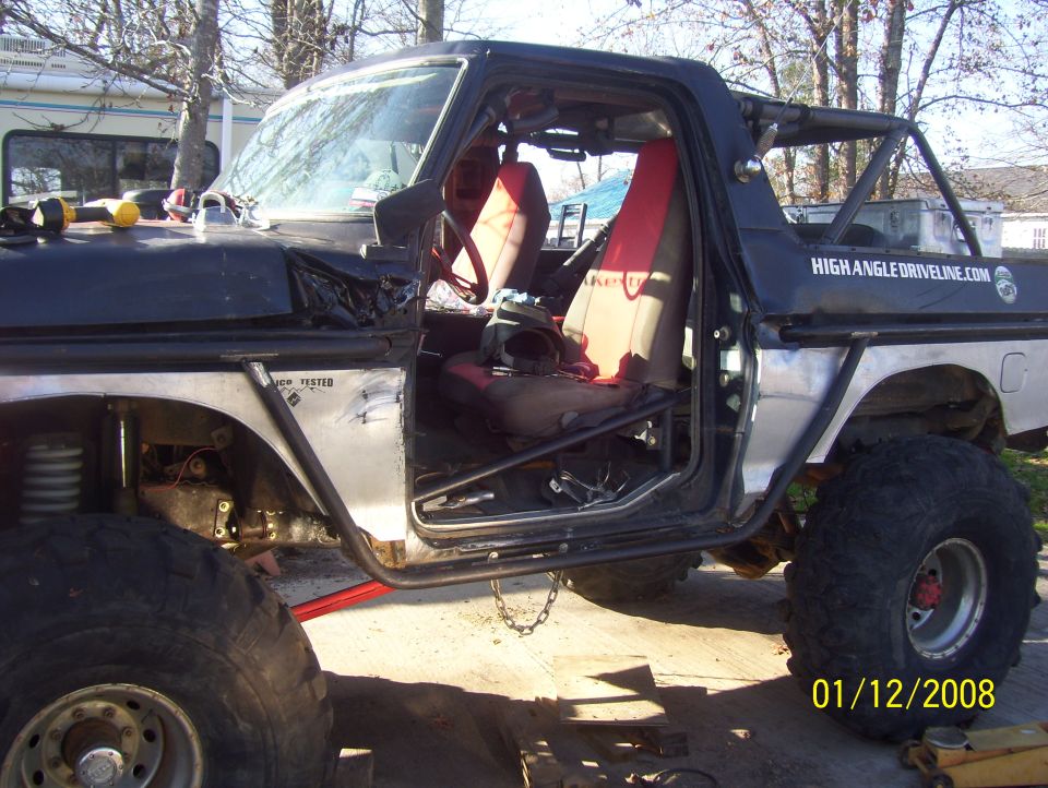 Black 1978 Ford Bronco interior with red seats, roll cage, and large tires