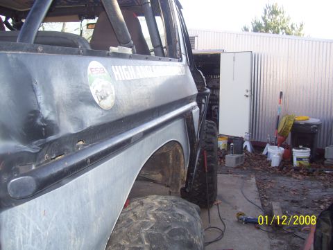 1978 Ford Bronco - This heavily modified off-road vehicle features a roll cage and is parked in a yard with a metal shed in the background.