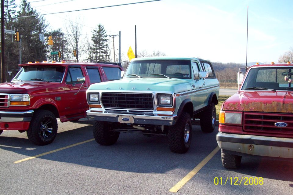 Lifted mint-green Ford Bronco parked between two red Ford pickups, dated 01/12/2008