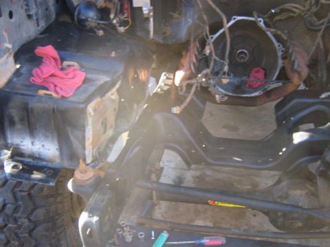 1986 Ford Bronco - The engine bay of a vehicle is shown with the engine removed, revealing the frame and transmission housing.