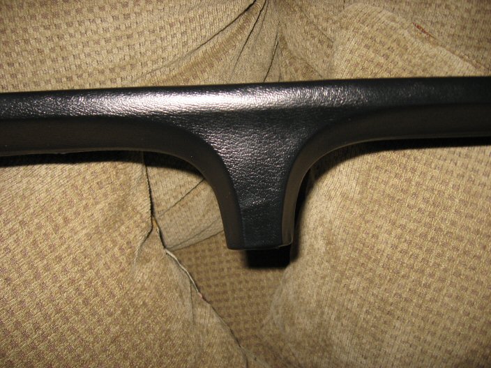 Black dashboard trim piece against tan upholstery