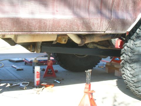 1979 Ford Bronco - The vehicle's undercarriage is visible, supported by jack stands with tools scattered around.