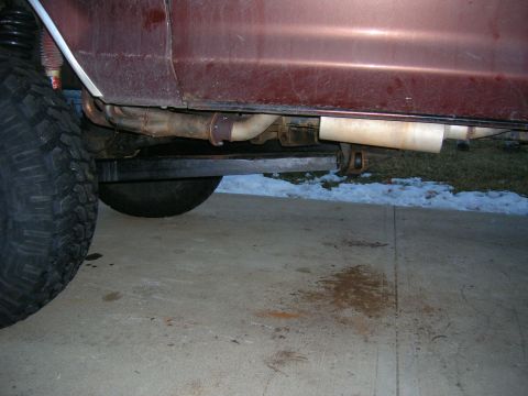 1979 Ford Bronco - Close-up view of the exhaust system and a large tire on the side of a maroon vehicle.
