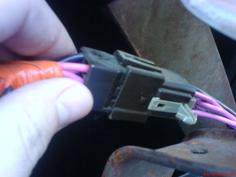 1986 Ford Bronco - A hand holds orange-taped wires connected to a black electrical connector with purple wires.